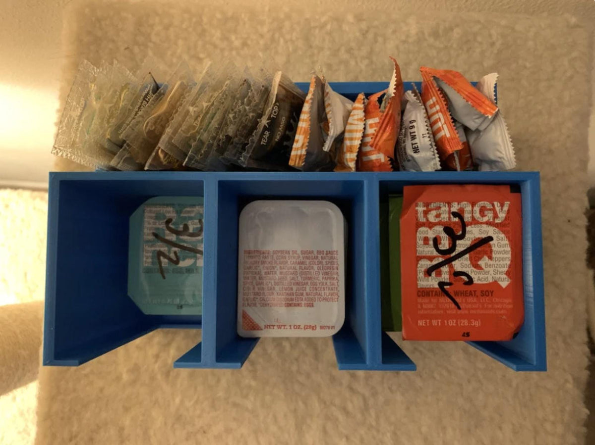 Three-compartment to-go sauce holder filled with condiment packets