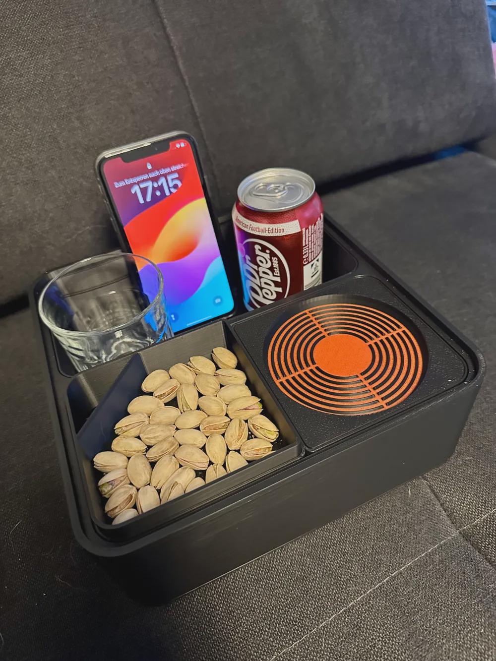 Phone snack caddy with smartphone, drink, and pistachios on a couch