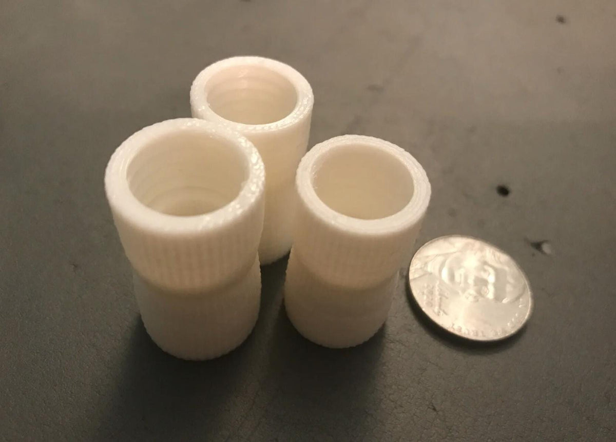 White toothpaste transfer adapters shown with a coin for scale