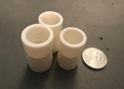 White toothpaste transfer adapters shown with a coin for scale