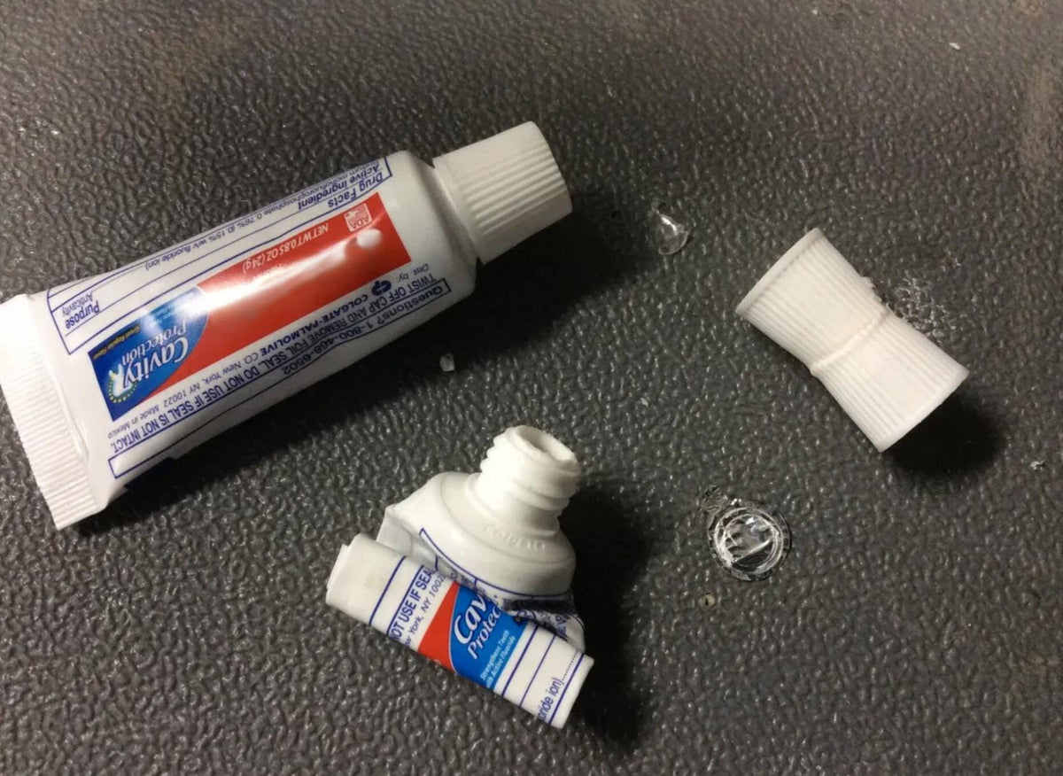 Toothpaste transfer adapter beside two toothpaste tubes